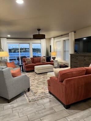 Relax in a comfortable seating area with a sofa and armchairs, enjoying a scenic view of a body of water and greenery.