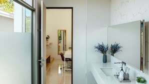 A modern bathroom with a glass shower enclosure, a large mirror, and a white vanity.