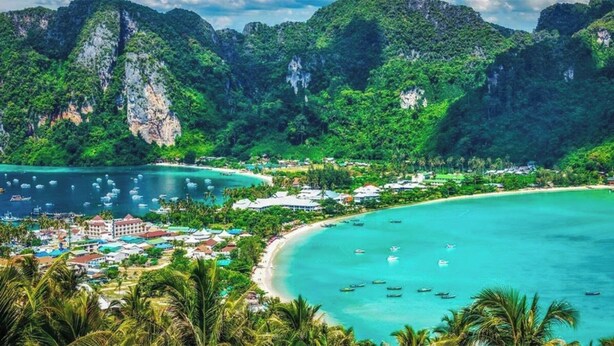 A coastal resort with a beach, clear turquoise waters, and lush greenery.