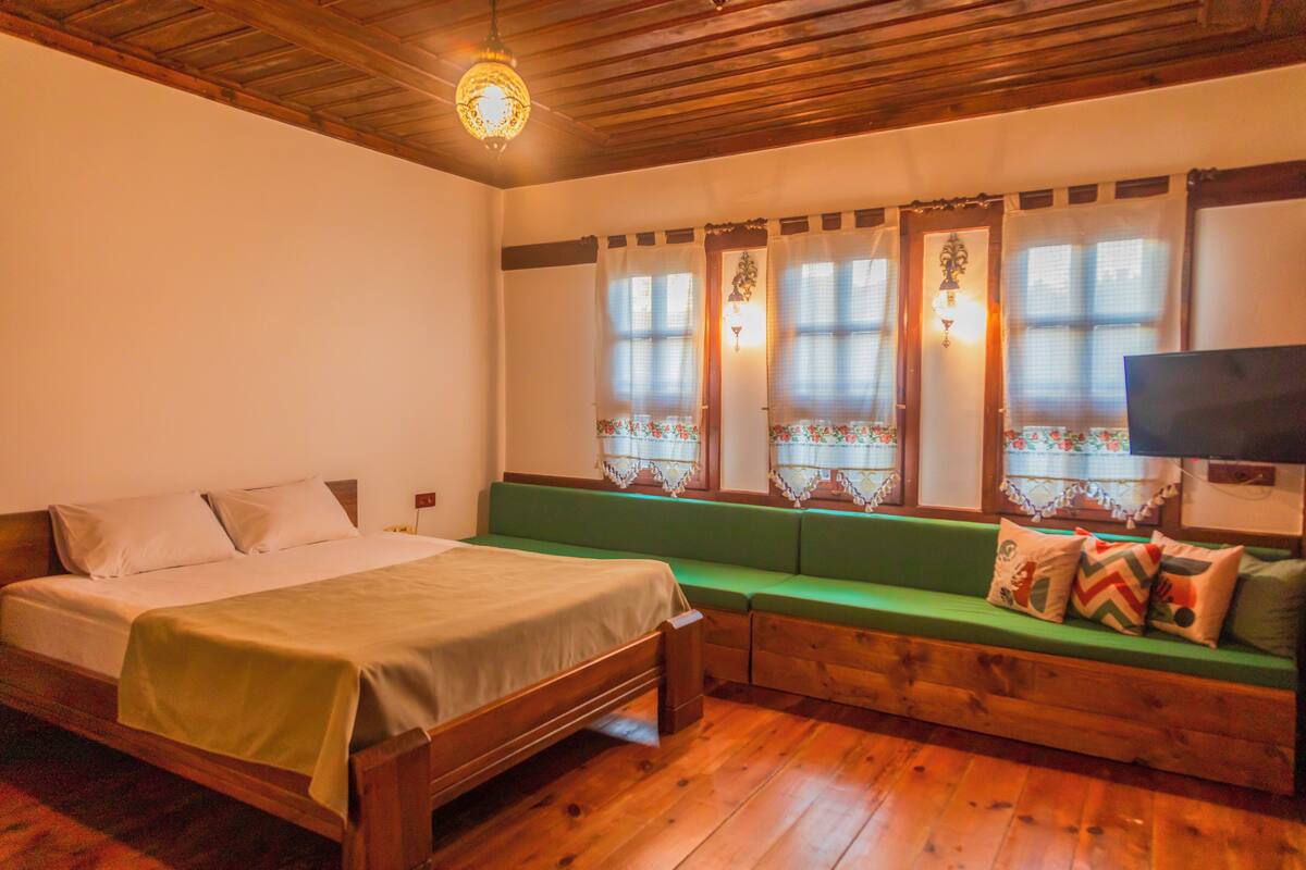 A room with a bed, a green bench, and a TV.