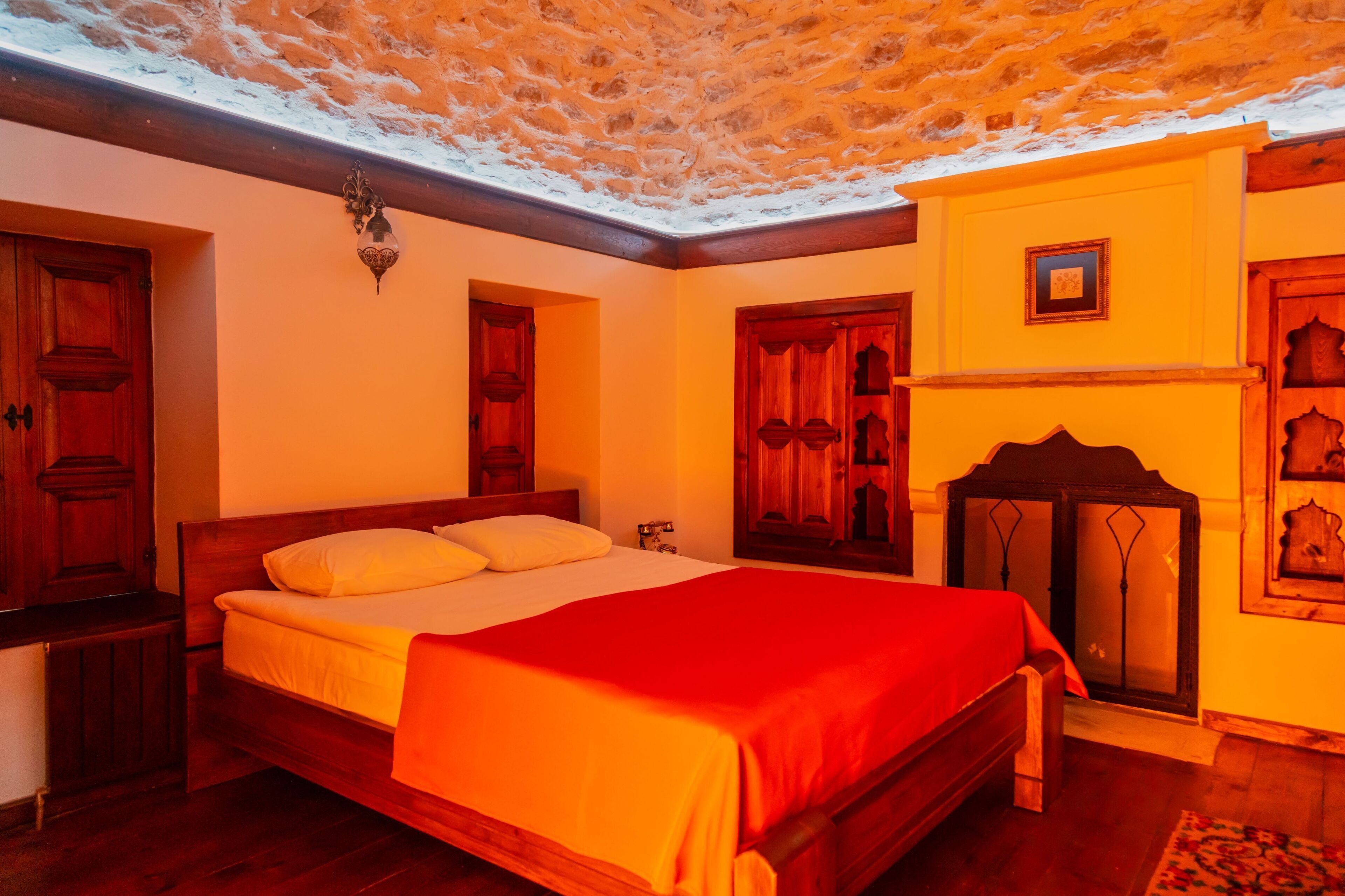 A room with a wooden bed, a fireplace, and a stone ceiling.