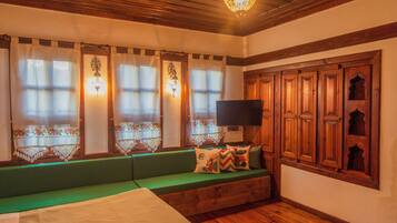 A cozy room with a green sofa, wooden cabinets, and a television on a stand.