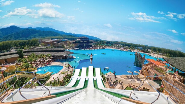 A resort with multiple swimming pools, a large water slide, and a mountainous backdrop. - The Phana (Si Sunthon)