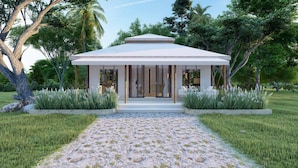 A modern building with a covered entrance, surrounded by lush greenery and a gravel pathway. - The Phana (Si Sunthon)