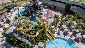 An aerial view of a water park with multiple slides and pools, surrounded by palm trees and lounge areas. - The Phana (Si Sunthon)