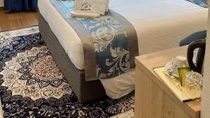 A well-lit bedroom with a large bed, a window with curtains, a nightstand, and a wall-mounted light fixture. - Hotel white swan (Wormeldange)