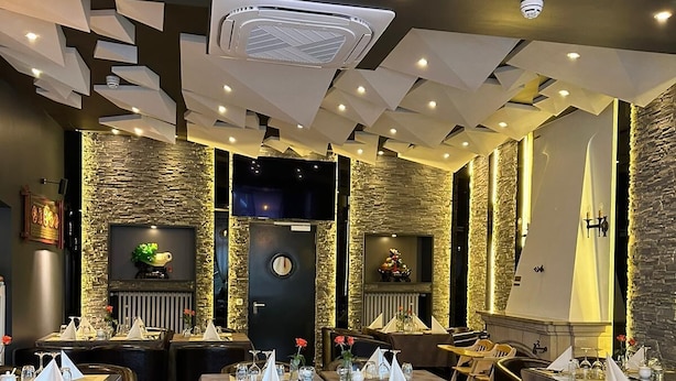 A restaurant with tables set for dining, stone walls, and a modern ceiling design. - Hotel white swan (Wormeldange)
