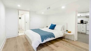 Une chambre à coucher avec un lit, une table de chevet et une vue sur la cuisine.