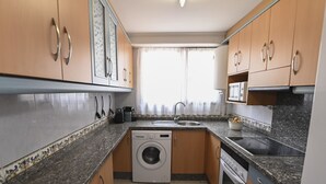 Eine kleine Küche mit Waschmaschine, Mikrowelle, Spüle und Backofen.