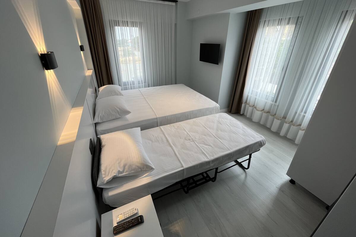 A modern hotel room with a large bed, a flat-screen TV, and a bedside table with a remote control.