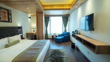 Une chambre d’hôtel avec un lit, une télévision, un canapé et un meuble en bois pour la télévision.