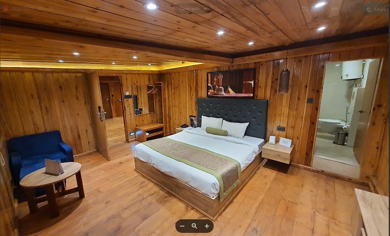 Ein Zimmer mit Holzwänden, einem Bett, einem blauen Sofa, einem kleinen Tisch und einem Spiegel.