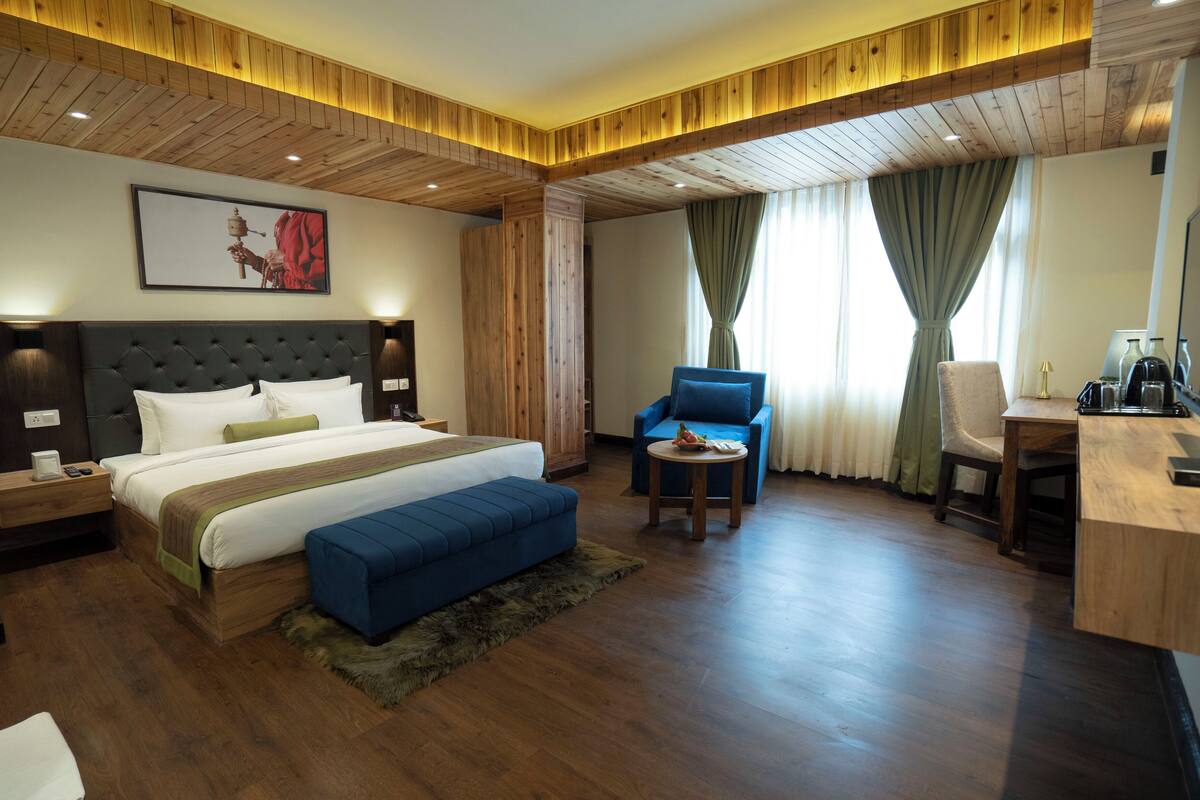 A modern hotel room with a large bed, a desk, a chair, and a sofa.