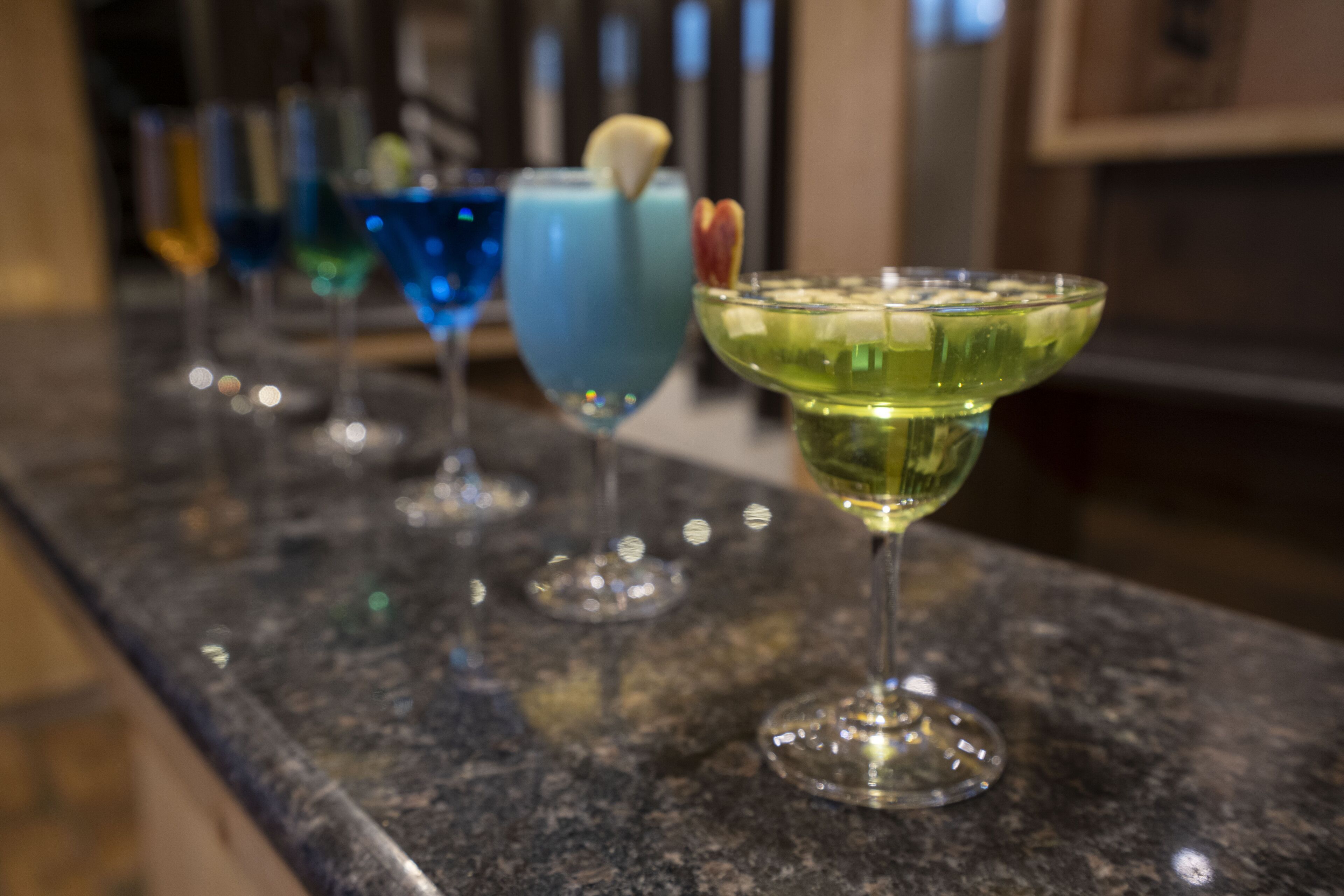 A bar counter with various colorful cocktails.