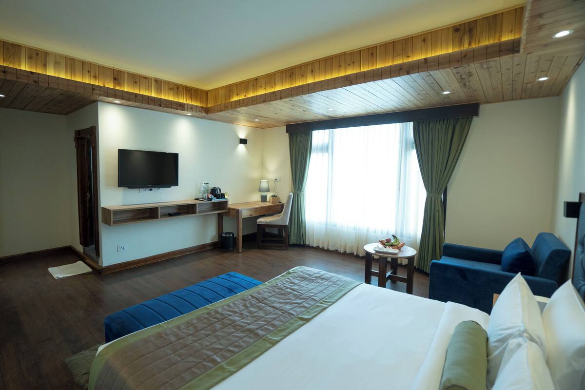 A hotel room with a bed, a desk, a TV, and a seating area.