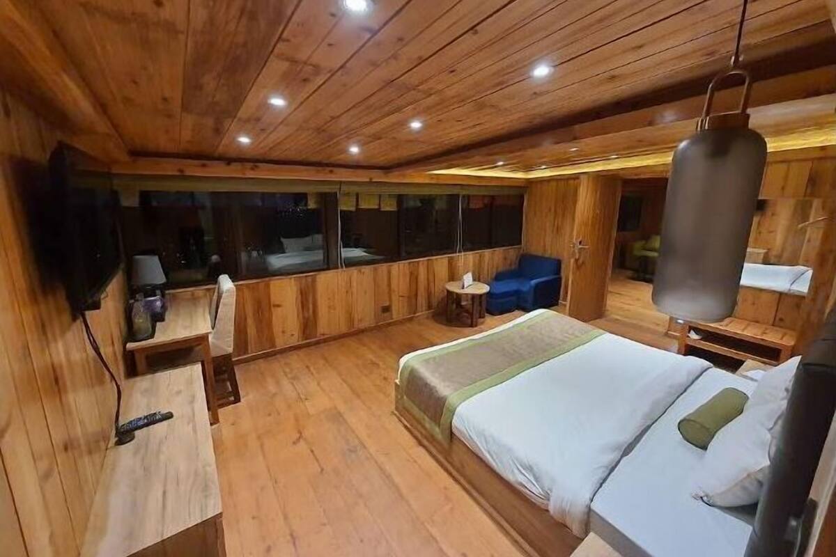 A wooden-themed bedroom with a bed, bedside tables, a desk, and a hanging punching bag.