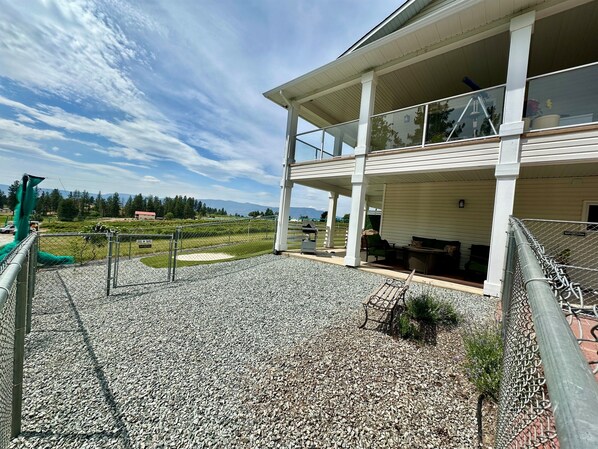 A two-story building with a covered patio area, a gravel ground, and a view of a mountainous landscape.