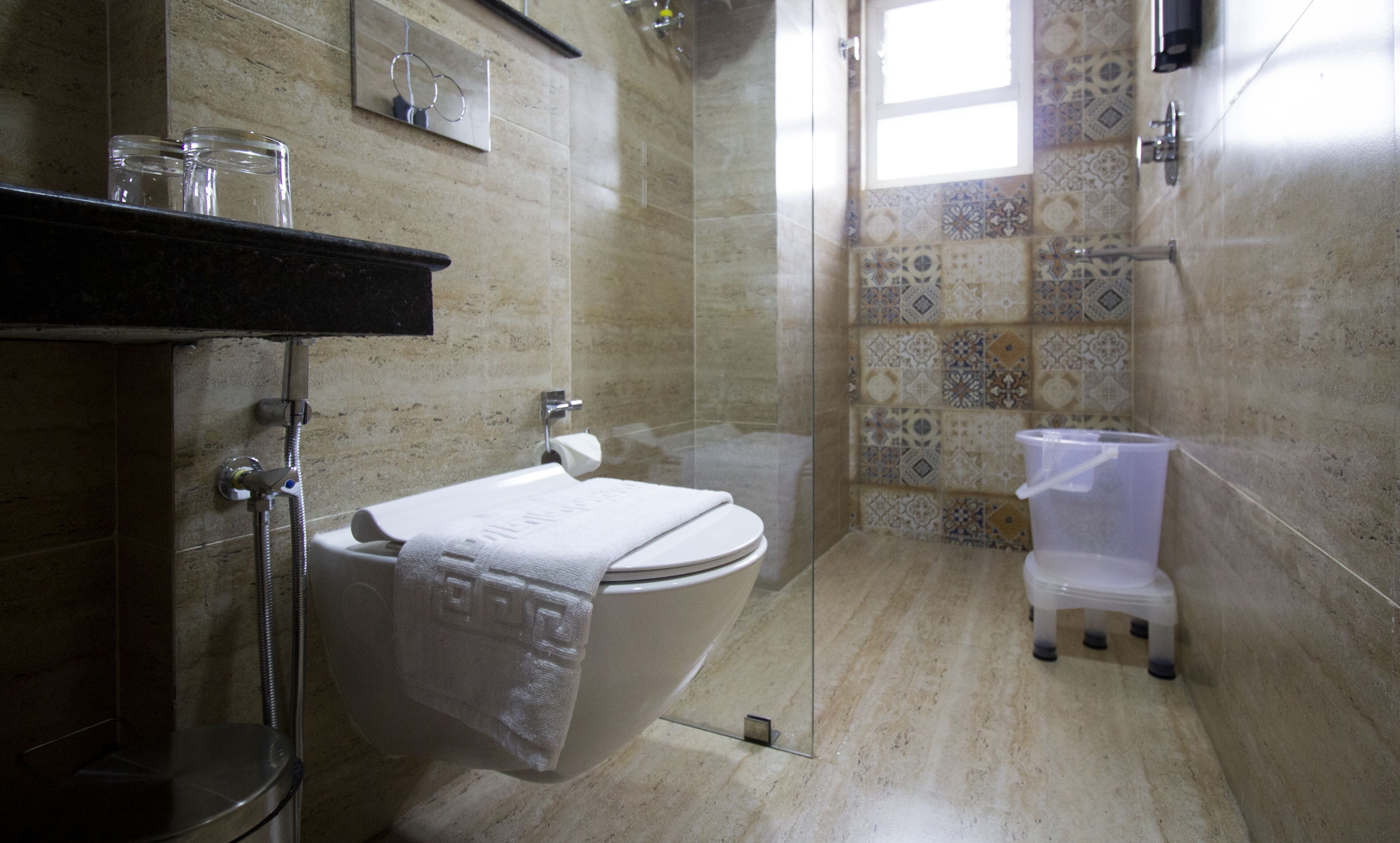 Un baño con inodoro, cabina de ducha de vidrio y un pequeño cubo de basura.