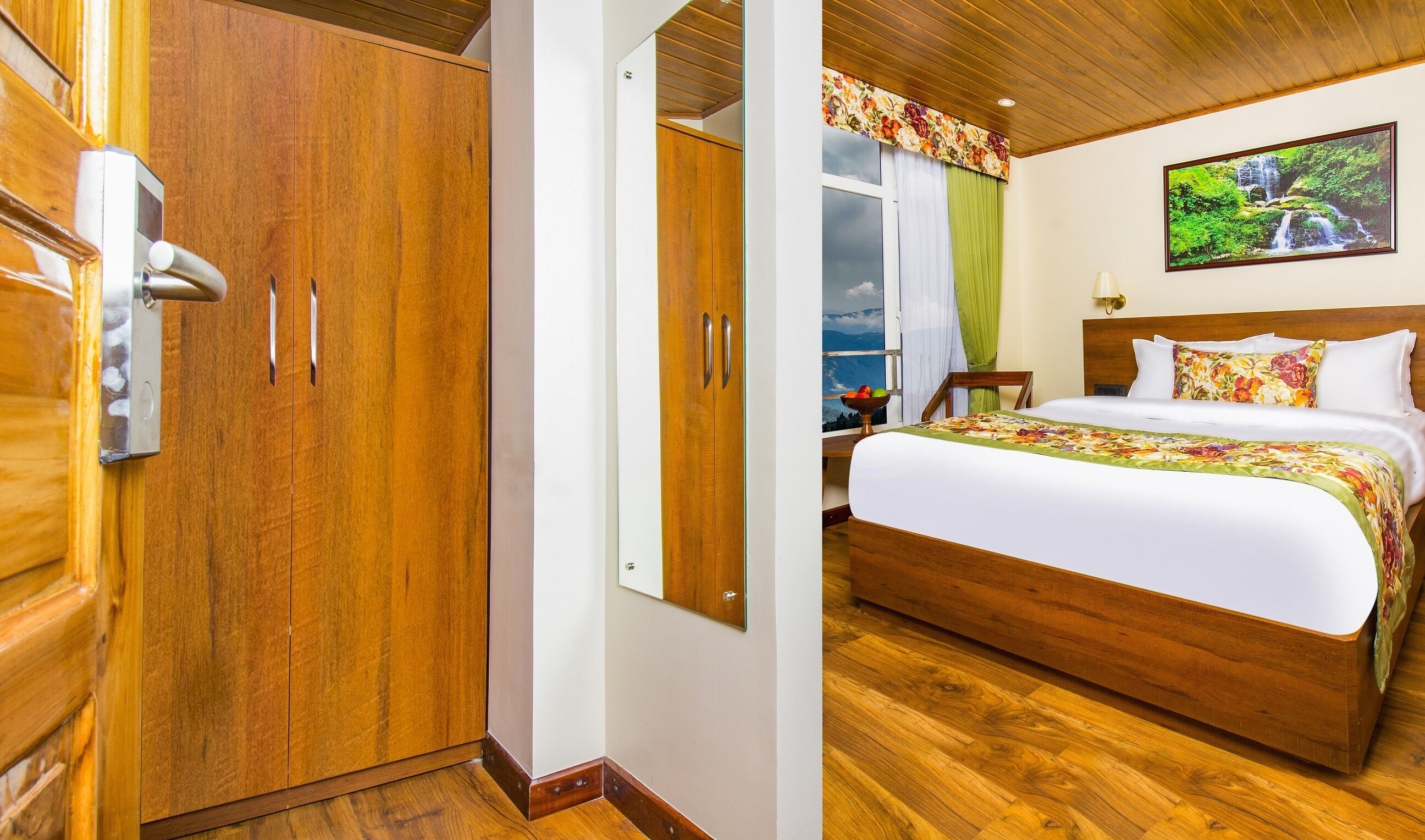 A wooden door with a handle and a keyhole, a bed with a floral bedspread, and a painting of a waterfall on the wall.