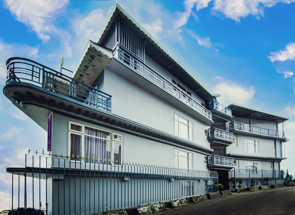 Um edifício de dois andares com varandas, telhado plano e cerca de metal.