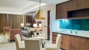 Una sala de estar moderna con una mesa de comedor de vidrio, dos sillas, un sofá y un panel decorativo en la pared.