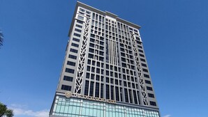 Un hotel alto con diseño moderno, que destaca por una entrada imponente y un amplio frente de vidrio.