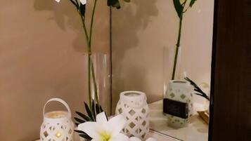 A bathroom vanity with a mirror, white towels, a small candle, and decorative plants.