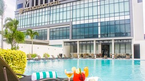 Un hotel con piscina, sillas de descanso y un bar con bebidas.