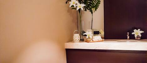 A hotel room with a bed, a mirror, a small plant, and candles.