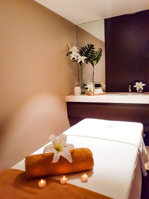 Una habitación de hotel con cama, espejo, planta pequeña y velas.