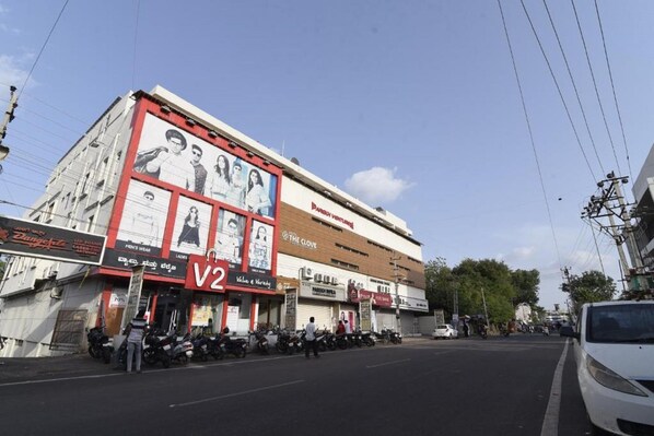 A street view with a building featuring a large advertisement and several shops.