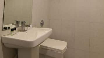 A bathroom with a white sink, mirror, and toilet.