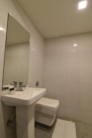 A bathroom with a white sink, mirror, and toilet.