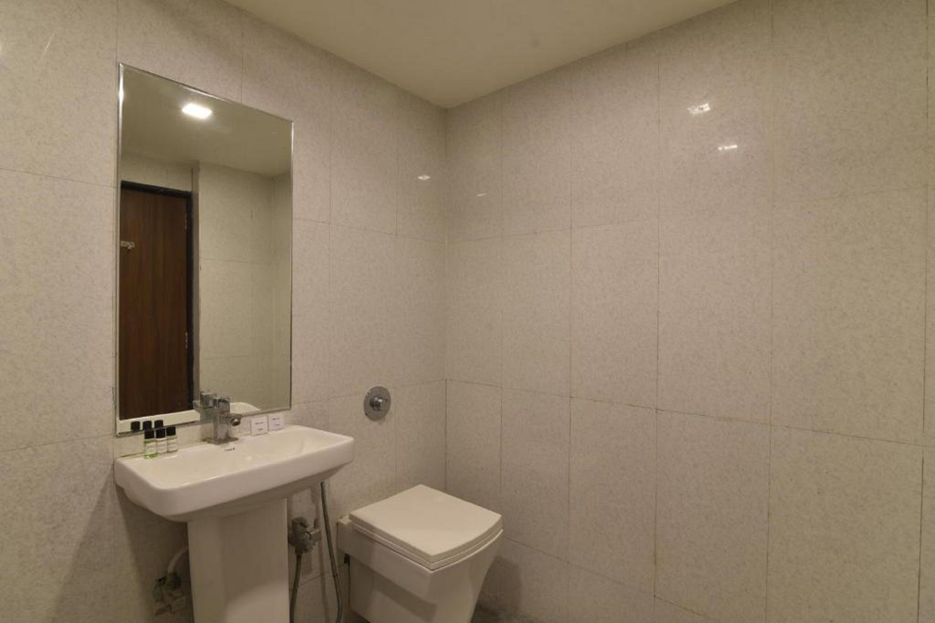 A bathroom with a white sink, mirror, and toilet.