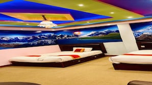 Habitación de hotel con dos camas, techo colorido y un mural con paisaje de montaña.