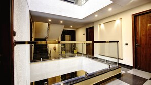 Un vestíbulo de hotel con barandilla de vidrio, piso a cuadros y puerta de madera.