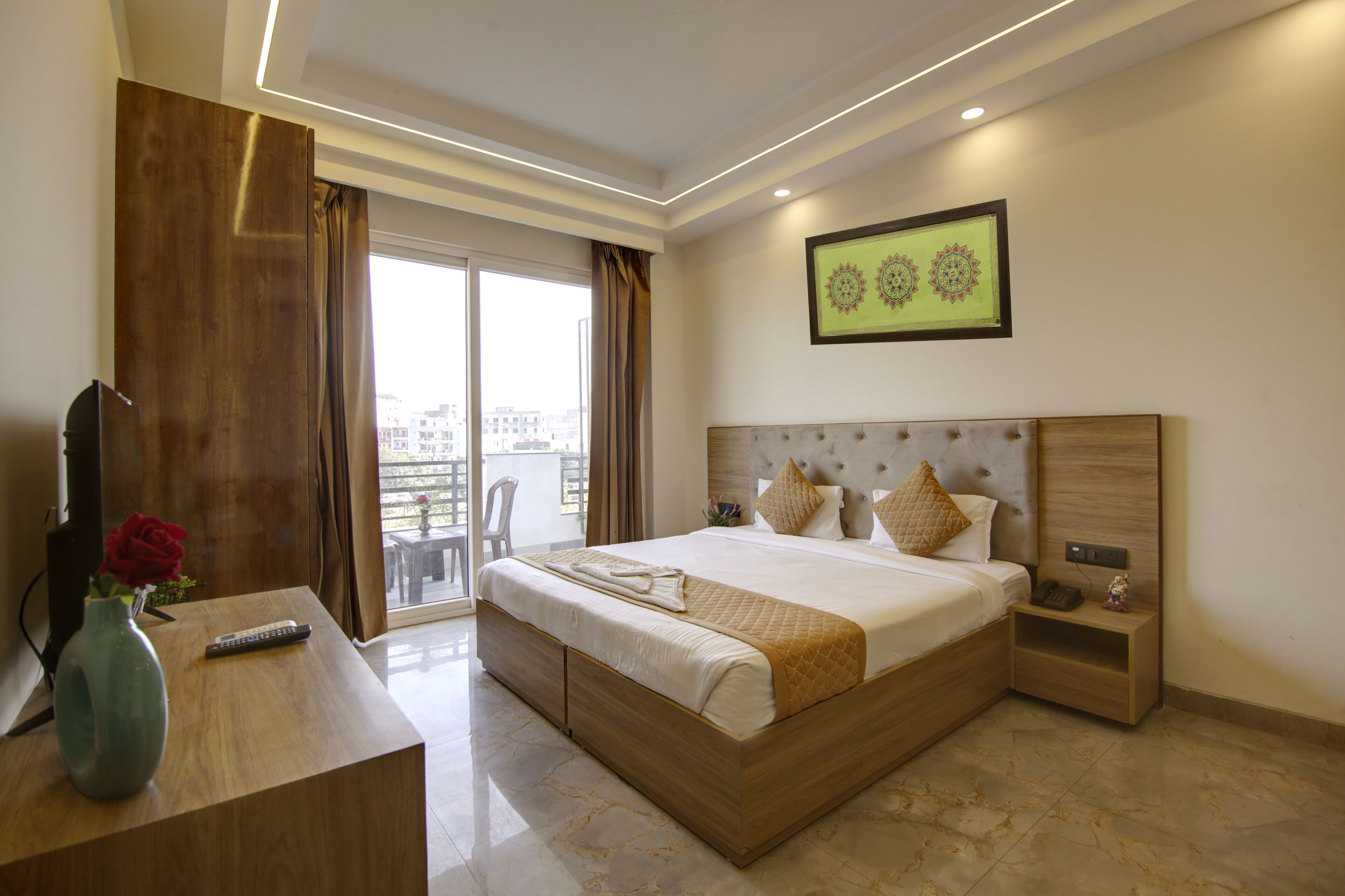 Ein modernes Hotelzimmer mit einem großen Bett, einem Holztisch, einer Vase mit einer roten Rose und Blick auf die Stadt durch das Fenster.