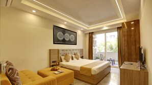 Una habitación de hotel moderna con cama, sofá, escritorio y un amplio ventanal con cortinas.