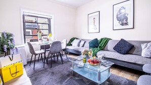 Un salon moderne avec un canapé, des fauteuils, une table basse en verre et des œuvres d’art accrochées aux murs.