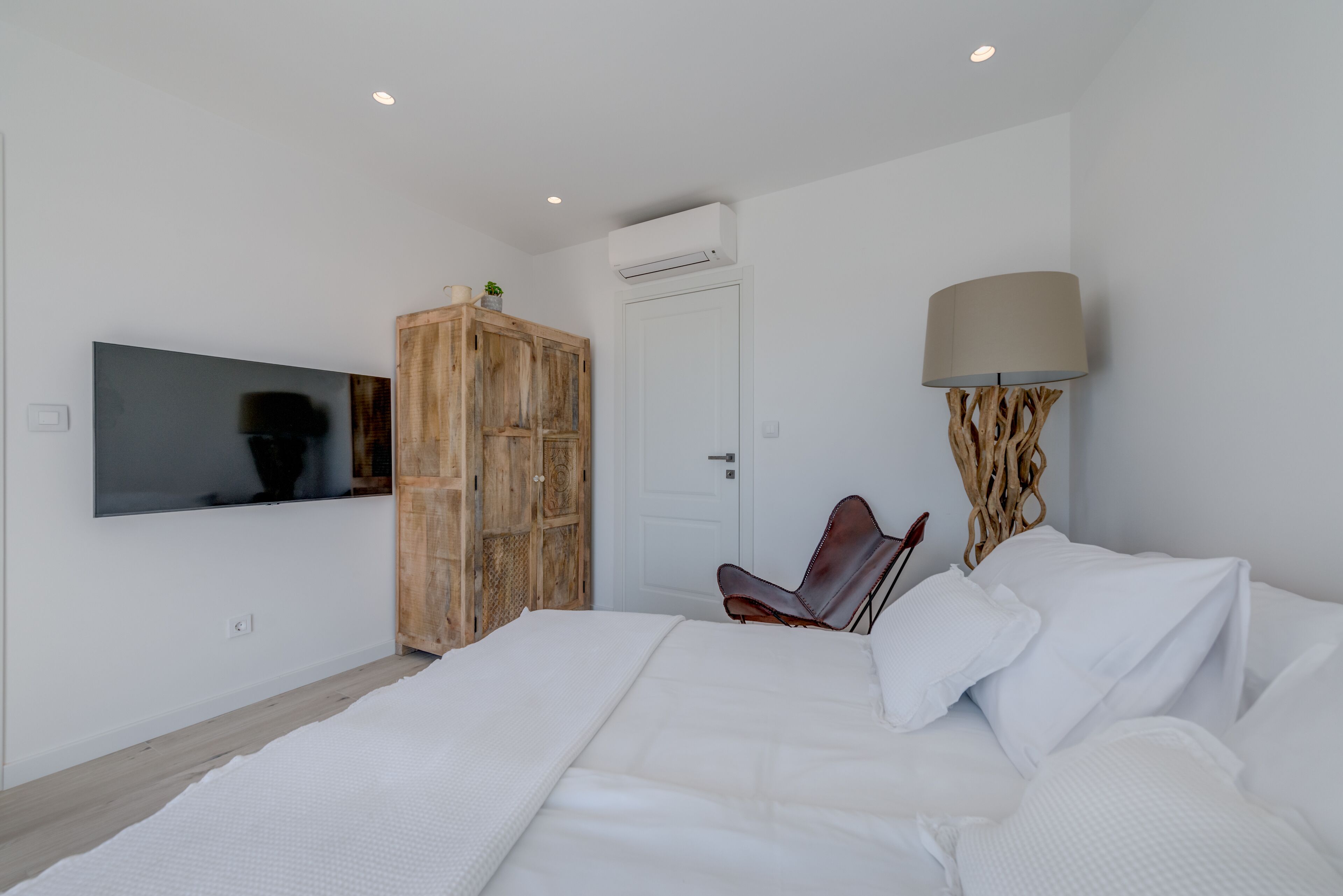 Ein modernes Schlafzimmer mit einem großen Bett, einem Holzschrank, einem Fernseher und einer Lampe.