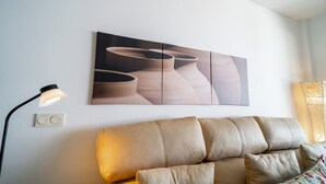 A modern living room with a sofa, a wall-mounted lamp, and a large abstract painting.