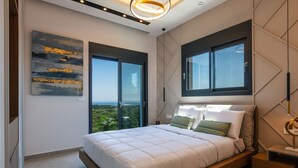 A modern bedroom with a large bed, two windows, a view of greenery, and a ceiling light fixture. - Grand Luxe Villa - Sea views, hot tub, private pool & modern design (Chania)