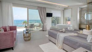Ein modernes Schlafzimmer mit einem großen Bett, einem rosa Sofa, einem Glastisch und Meerblick.