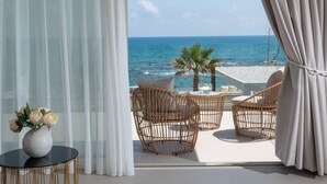 Ein Balkon mit Korbstühlen, einem kleinen Tisch mit Blumenvase und Blick auf das Meer.