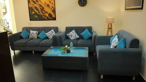 Una sala de estar moderna con dos sofás grises, una mesa de centro de vidrio y una mesita auxiliar con una lámpara.