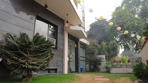 Un edificio moderno con patio empedrado, plantas en macetas e iluminación exterior.