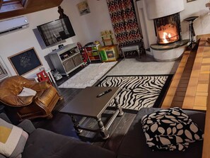 A cozy living room with a fireplace, a television, a sofa, and a coffee table. - A 3 min du Parc de Sainte-croix de Rhodes! Grand Gîte Familial, Avec Aire de jeu (Rhodes)