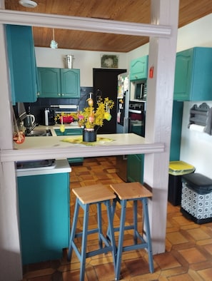 A kitchen with teal cabinets, a wooden countertop, and two stools. - A 3 min du Parc de Sainte-croix de Rhodes! Grand Gîte Familial, Avec Aire de jeu (Rhodes)