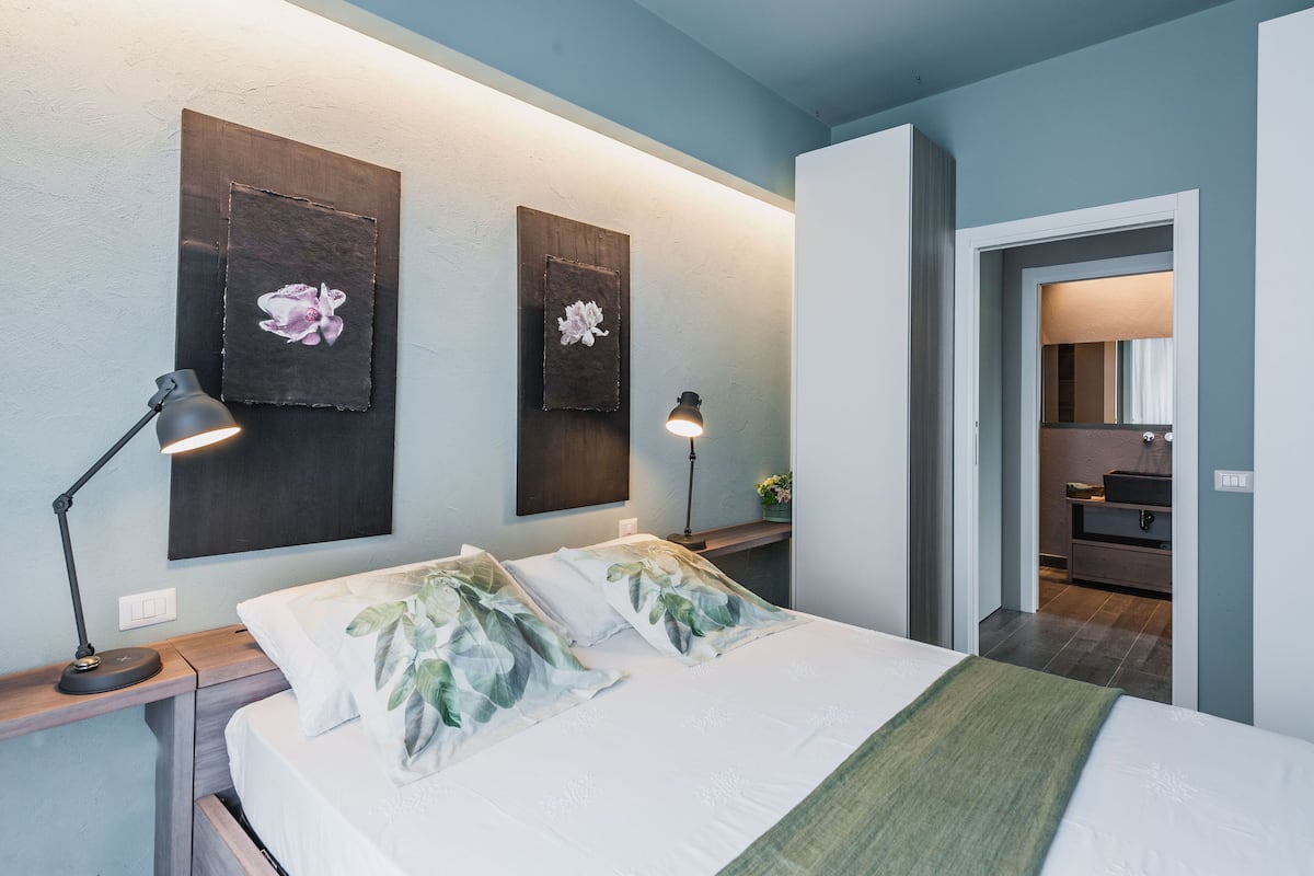 Ein Schlafzimmer mit einem Bett, zwei Wandlampen und einem Nachttisch mit einer Lampe.