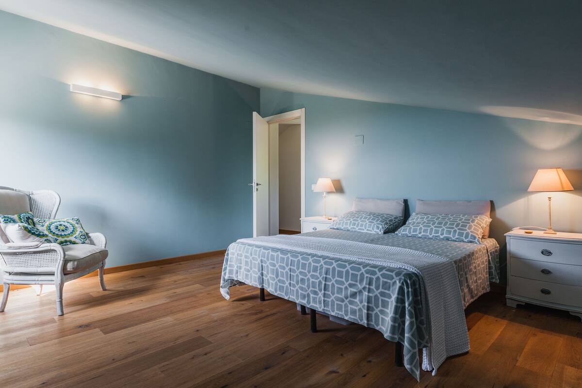 Ein Schlafzimmer mit einem Bett, zwei Nachttischen, einem Sessel und einem Beistelltisch.